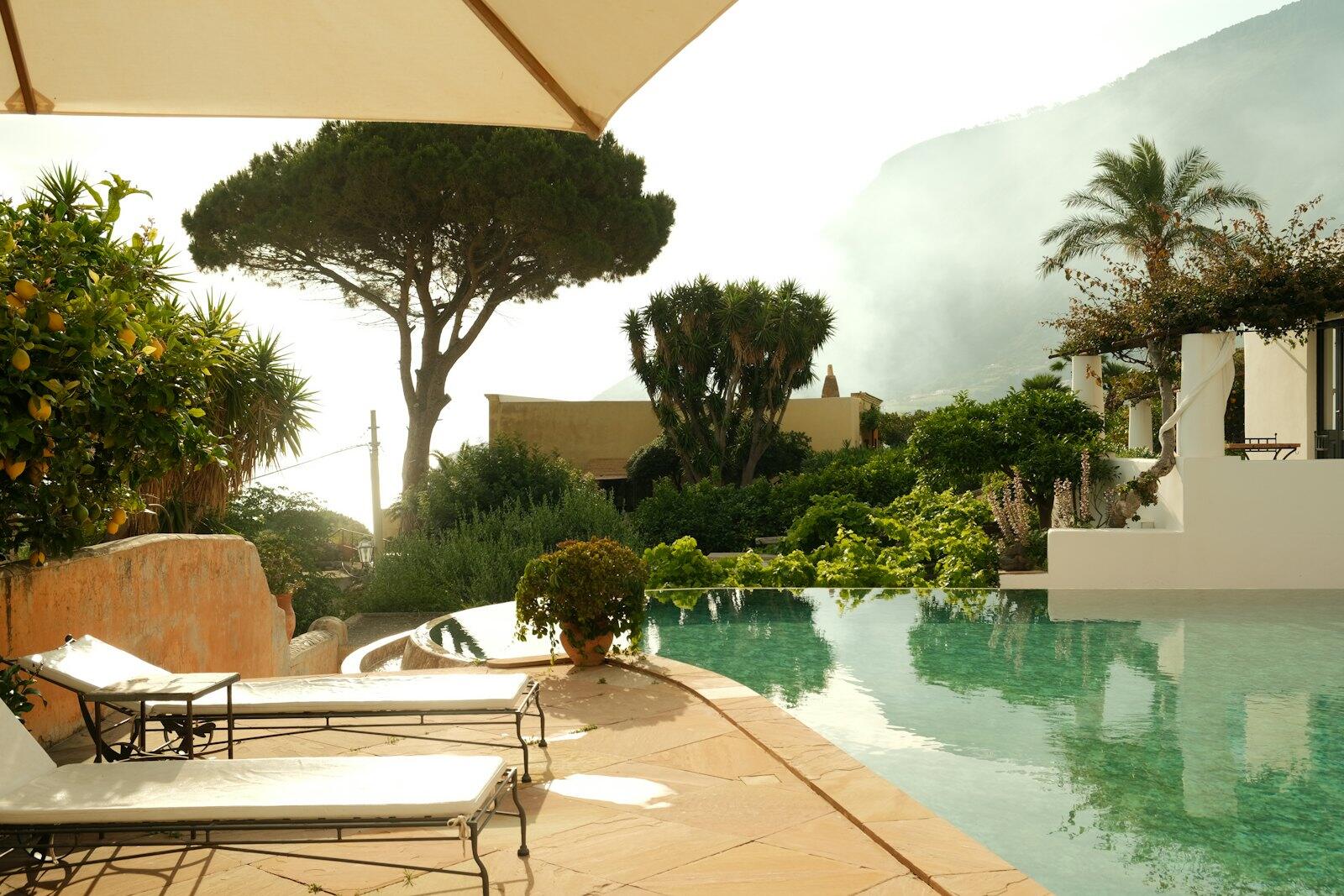 A luxury pool and loungers in a garden — illustrative property style — illustrative style for Liguria Bay House