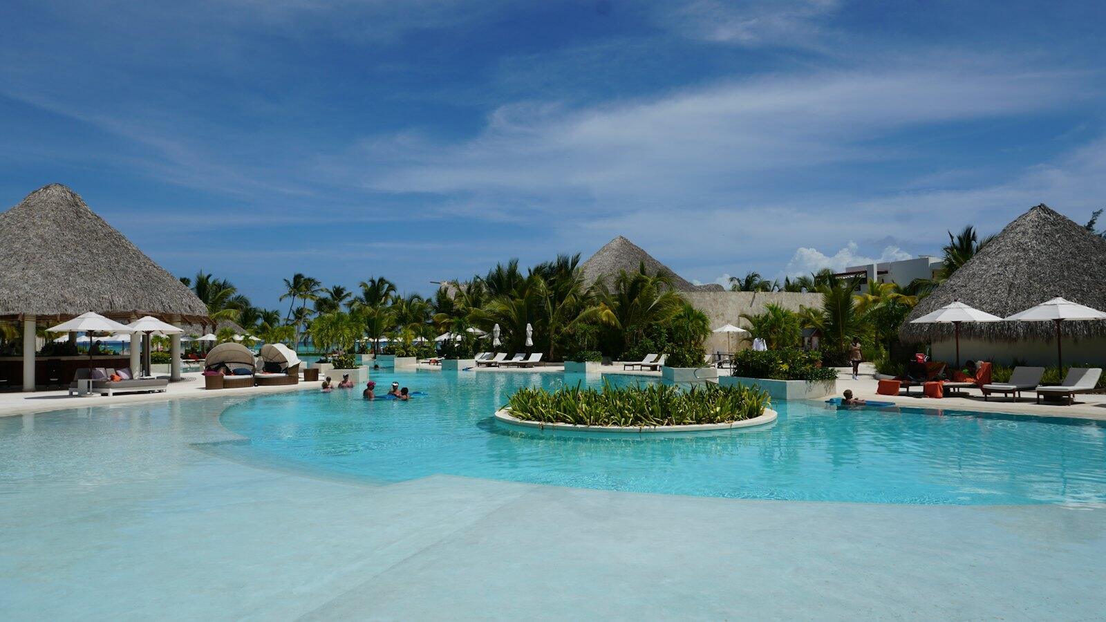 A resort pool with lounge chairs and thatched umbrellas — illustrative property style — illustrative style for Tamarind Court