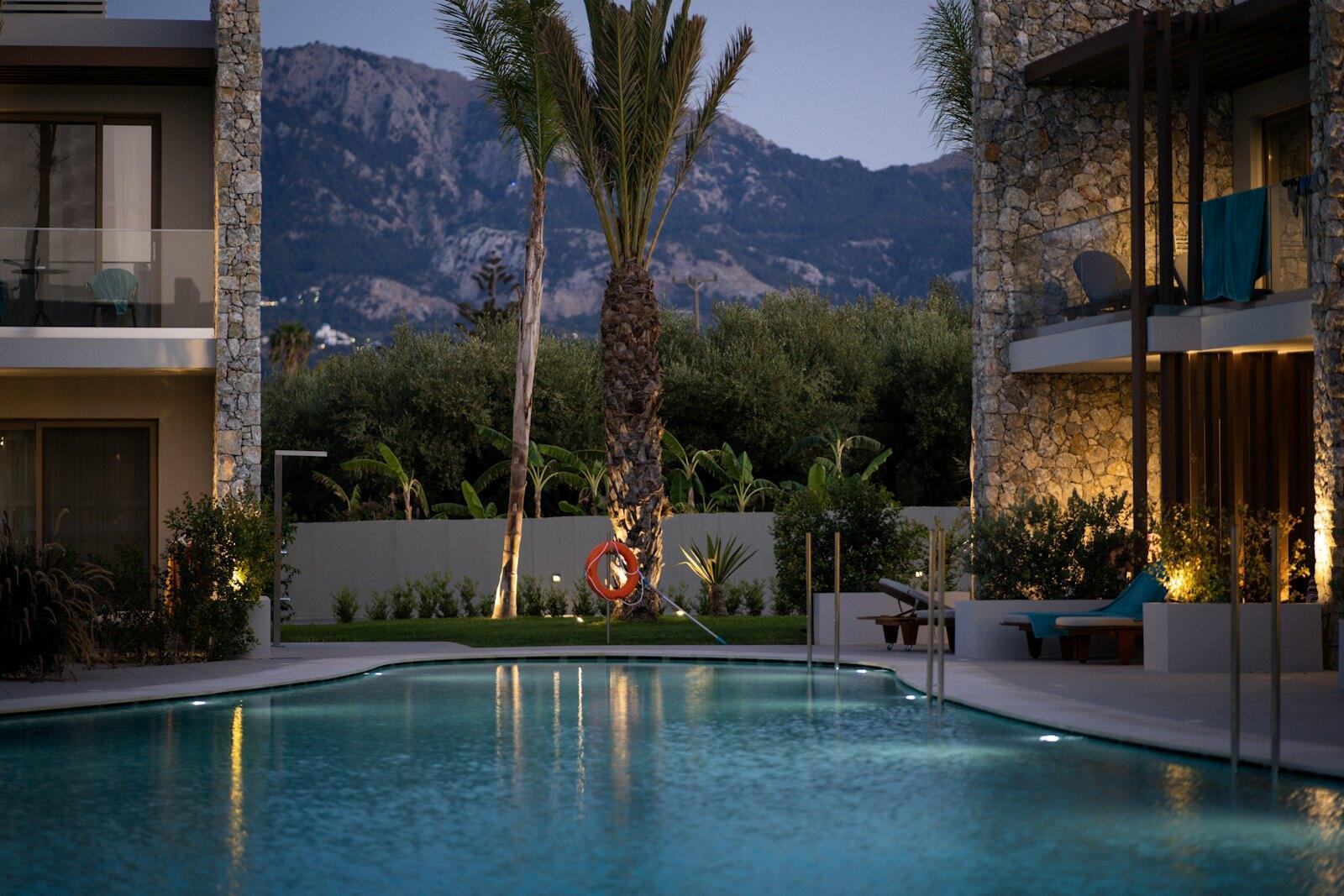 a swimming pool surrounded by palm trees in front of a building — illustrative property style — illustrative style for Harbour Blue Villas