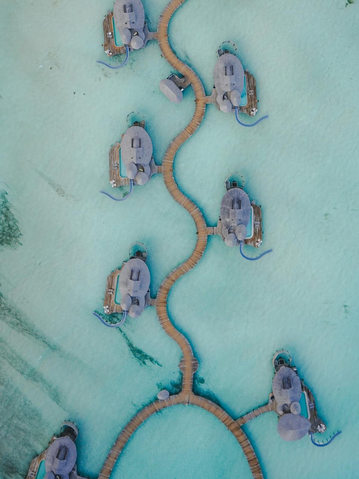 Overwater bungalows are connected by wooden walkways — illustrative property style — illustrative style for Bluewater Family Island
