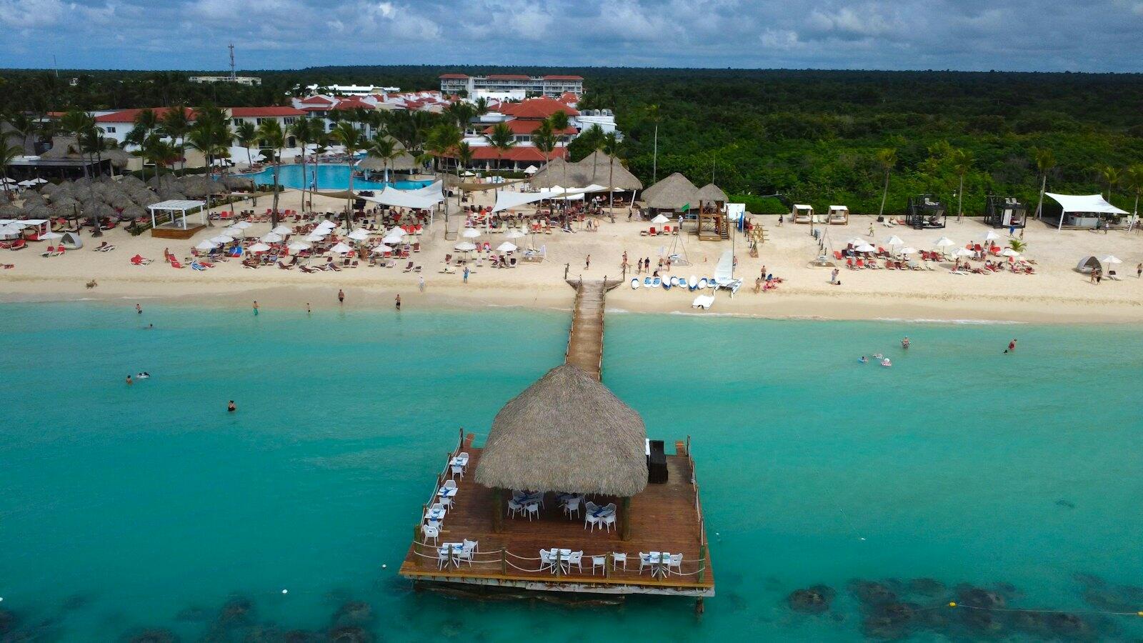 Tropical beach resort with thatched-roof bar and ocean view — illustrative property style — illustrative style for Driftwood Bay