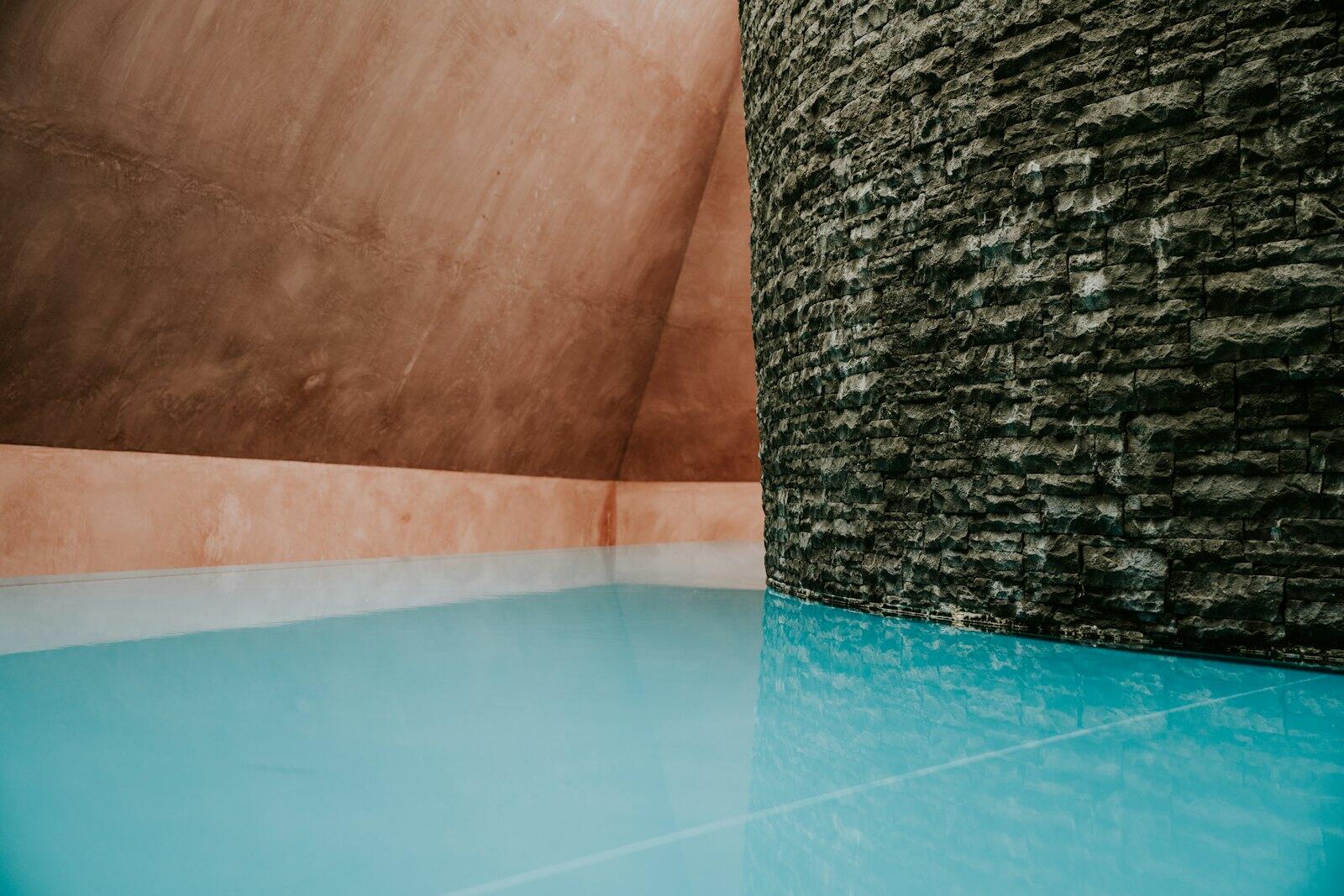a pool with a stone wall next to it — illustrative property style — illustrative style for Tasman Wilderness House