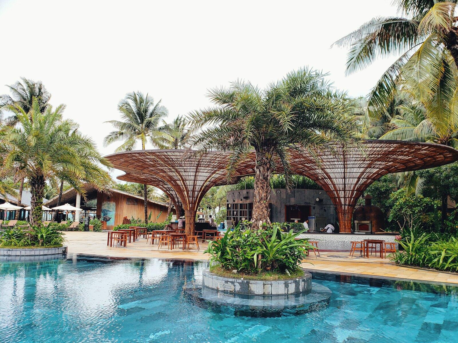 Two brown huts beside pool — illustrative property style — illustrative style for Hue River Residence