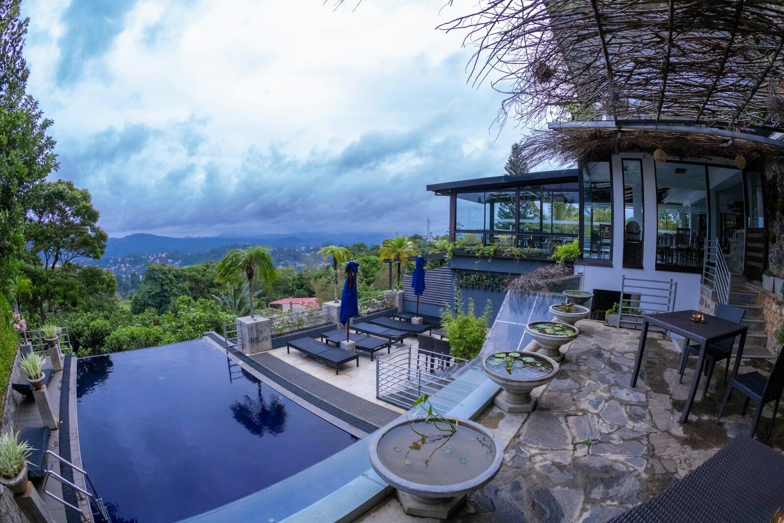 A large swimming pool surrounded by a lush green hillside — illustrative property style — illustrative style for Galle Courtyard