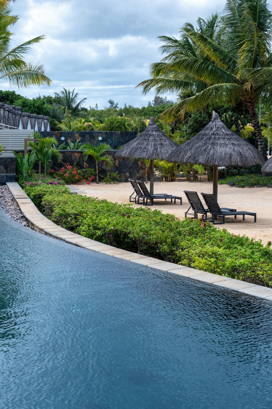 Infinity pool overlooking a tropical beach with palm trees — illustrative property style — illustrative style for Le Morne Garden House