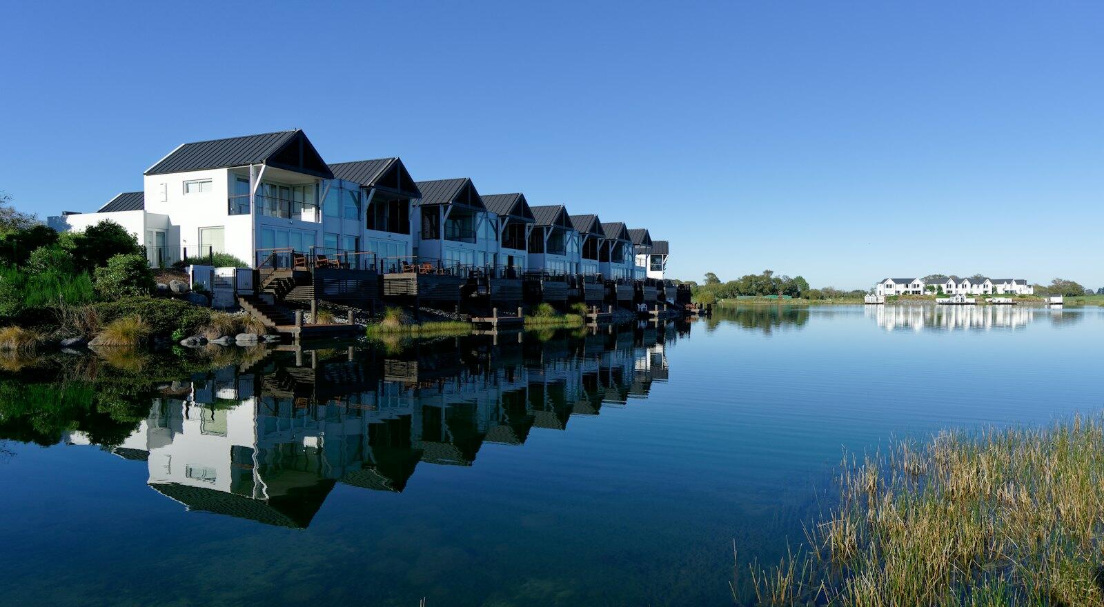 white and gray house beside body of water during daytime — illustrative property style — illustrative style for Rotorua Fern Retreat