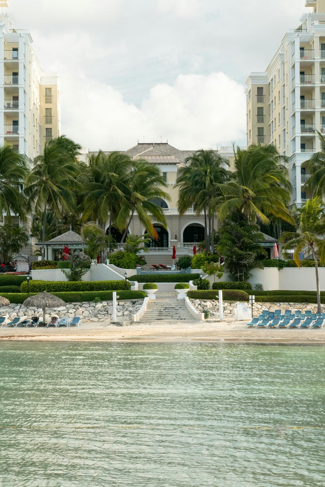A beach with a lot of lawn chairs and palm trees — illustrative property style — illustrative style for Blue Mountain House