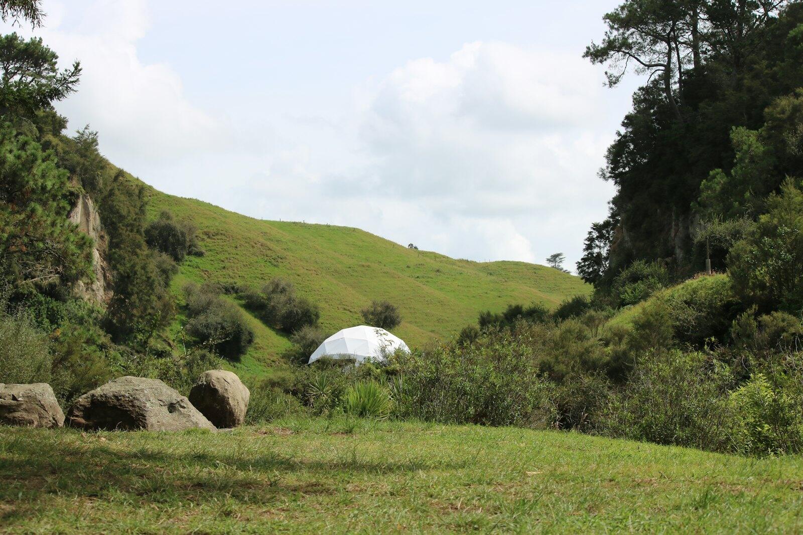 White dome structure nestled in a green, hilly landscape — illustrative property style — illustrative style for Queenstown Alpine Lodge