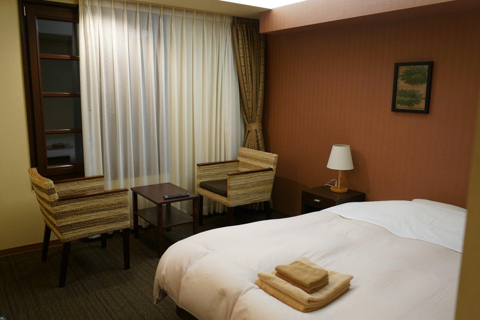 A hotel room with a bed and a chair — illustrative property style — illustrative style for Hakone Cedar Ryokan