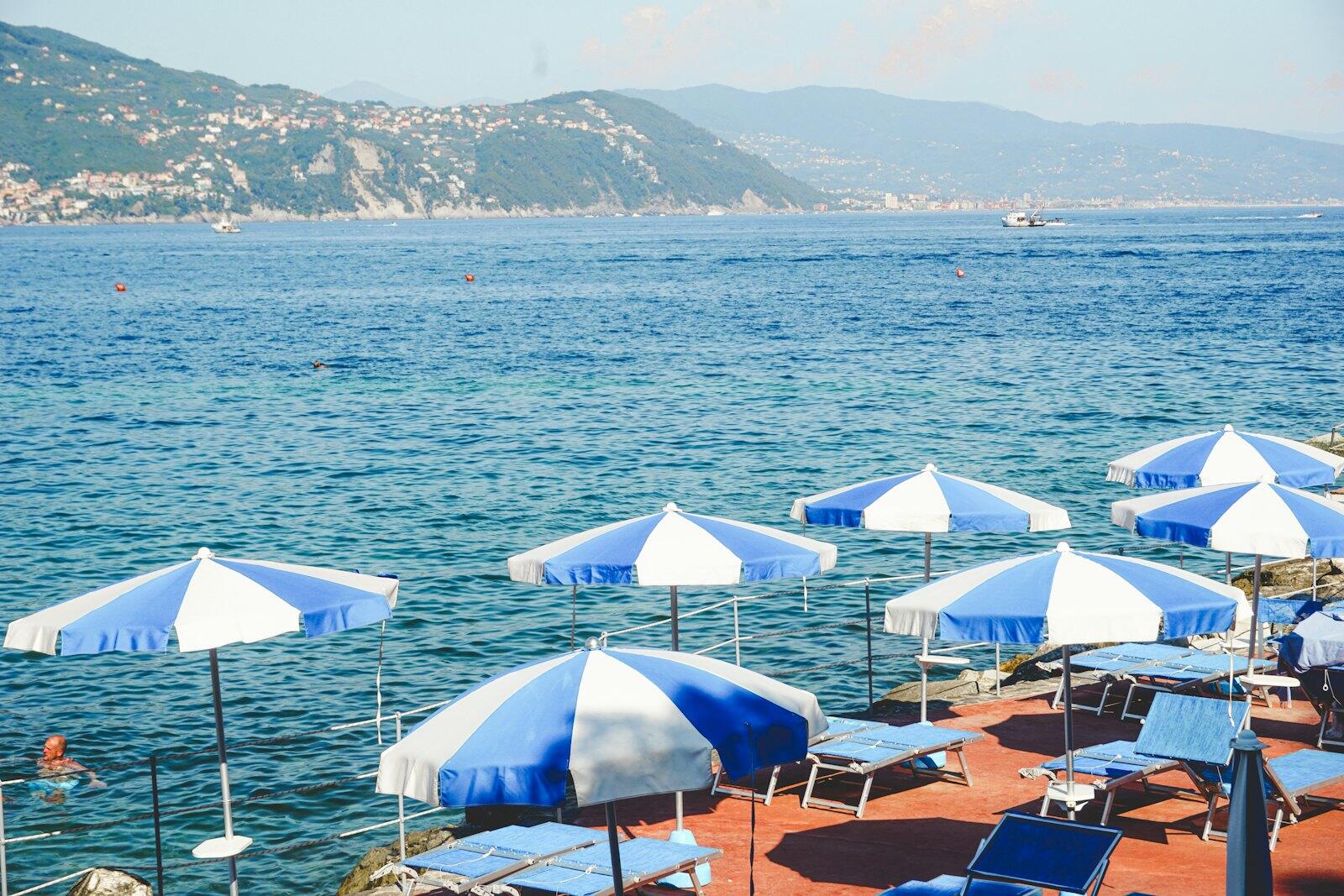 Beach umbrellas and lounge chairs by the blue ocean — illustrative property style — illustrative style for Garda Waterside House