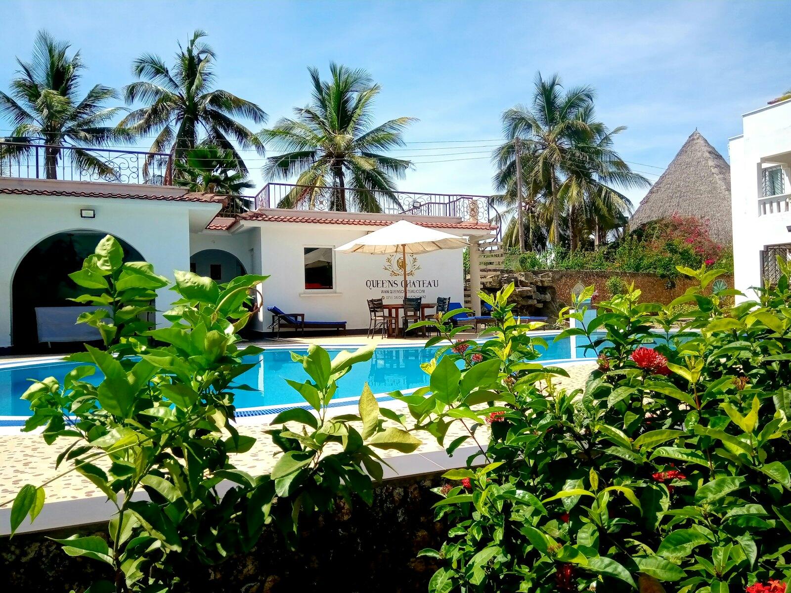 a hotel with a swimming pool surrounded by greenery — illustrative property style — illustrative style for Diani Palm Villas