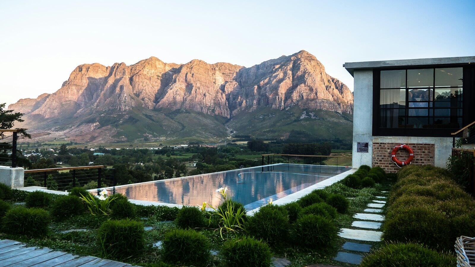 brown rock formation near building and swimming pool — illustrative property style — illustrative style for Franschhoek Orchard Retreat